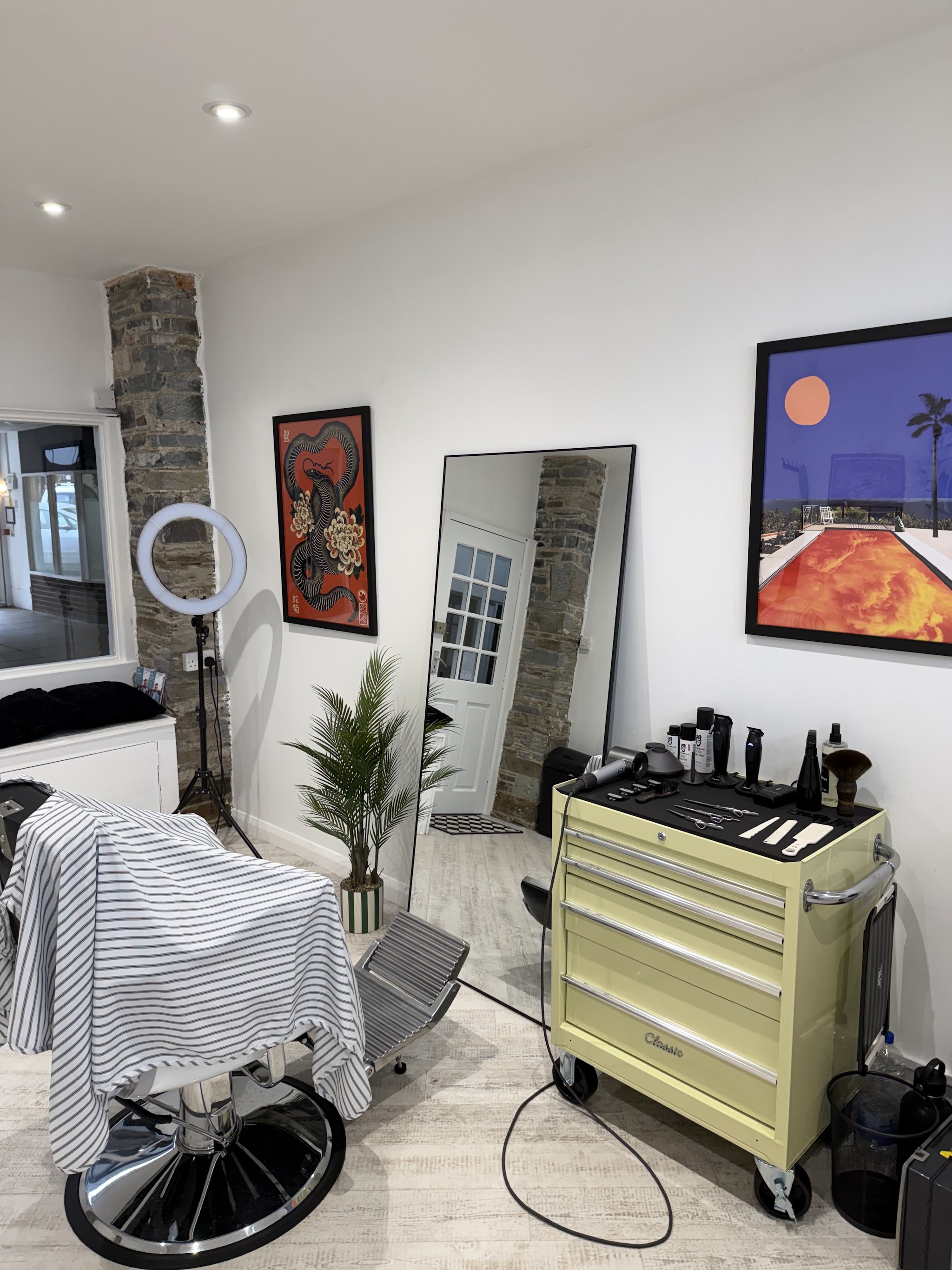 Inside the shop: the chair, a pale yellow tool trolley, ring light and artwork