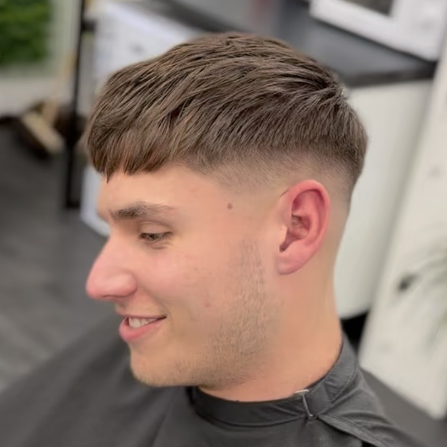 Fringe crop with a mid fade, client smiling in the chair